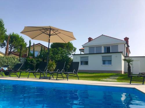 einem Pool mit Stühlen und einem Sonnenschirm neben einem Haus in der Unterkunft Apartmaji Meli Pu 2 in Izola