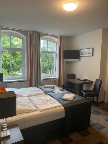 1 Schlafzimmer mit einem Bett, einem Schreibtisch und 2 Fenstern in der Unterkunft Seehotel Krakow am See in Krakow am See