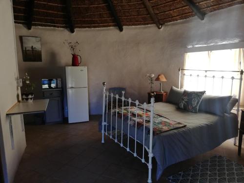 a bedroom with a bed and a refrigerator at Sheeprun Farmstay in Maclear