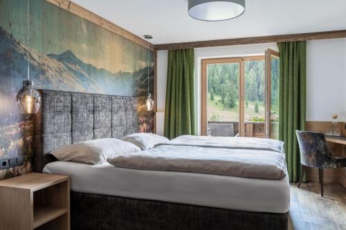 トゥクスにあるBerggasthaus Höllensteinhütteの大きなベッド付きのベッドルーム1室、壁に絵画が飾られています。