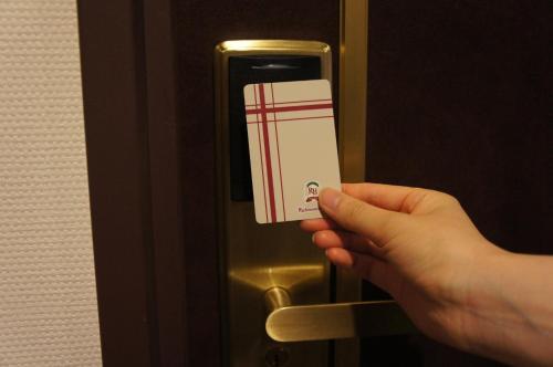 a person holding up a card on an elevator door at Richmond Hotel Miyazakiekimae in Miyazaki