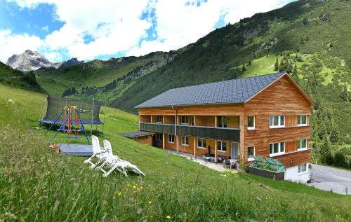 une maison en bois dans un champ avec une aire de jeux dans l'établissement Bergzeit Appartements, à Warth am Arlberg