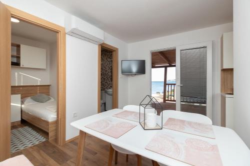 a room with a white table and chairs and a bedroom at Mobile home Sea Shell in Pašman