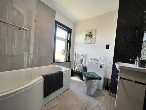 a bathroom with a tub and a toilet and a sink at Modern mid terrace villa, Royston, Barnsley in Royston