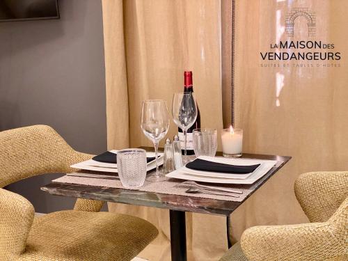 a table with two chairs and a wine bottle and glasses at La Maison des Vendangeurs - TABLE D'HÔTES le soir du jeudi au dimanche- Jacuzzi - Balnéo SPA - ACCES PISCINE pour toutes les chambres sauf STUDIO COQUET- Piscine de mai à mi-octobre in Martignargues