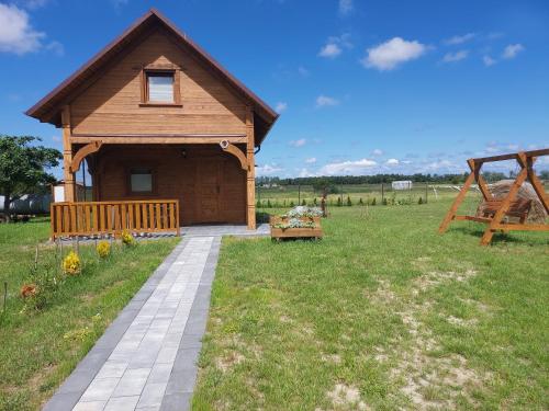 een klein houten huis met een loopbrug in een veld bij Przytulisko in Smołdzino