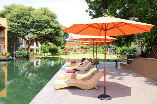 a group of chairs and an umbrella next to a pool at The Hotel Umbra Bagan in Bagan