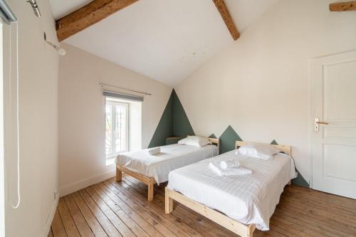 two beds in a room with two windows at Les Nuits Lupéennes in Lupé