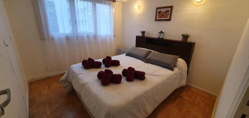 una habitación con una cama con tres almohadas rojas en Depto de 2 ambientes zona Guemes, en Mar del Plata