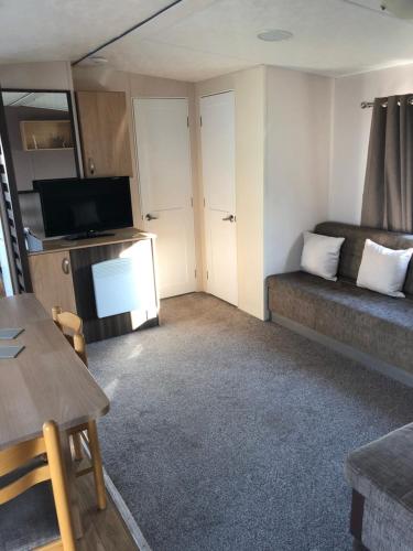 una pequeña sala de estar con sofá y TV en 8 Berth Caravan, en Clacton-on-Sea