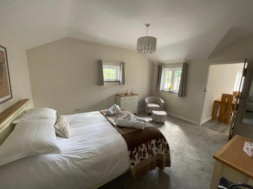 a bedroom with a large white bed and a chair at Sunnyside Cow Shed one bedroom central Cornwall in Truro