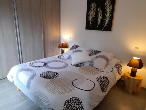 una camera da letto con un letto con un piumone bianco e nero di Ker jolly Maison au cadre naturel sans vis à vis a Plouégat-Guérand