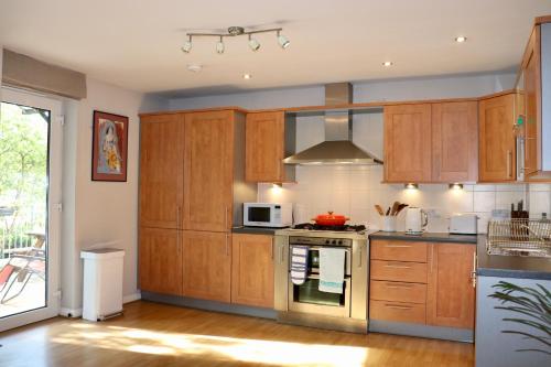 a kitchen with wooden cabinets and a microwave at LuxApartment - Port Of Leith - Free Parking in Edinburgh