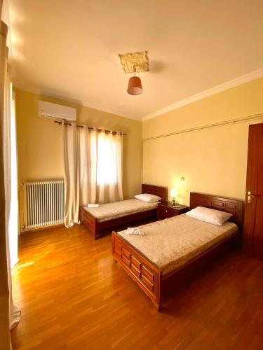 two beds in a room with wooden floors at Dimitris apartment in Diakopto