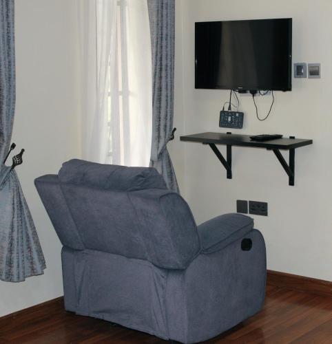 a living room with a chair and a television at The Cottage Residence Karen in Nairobi