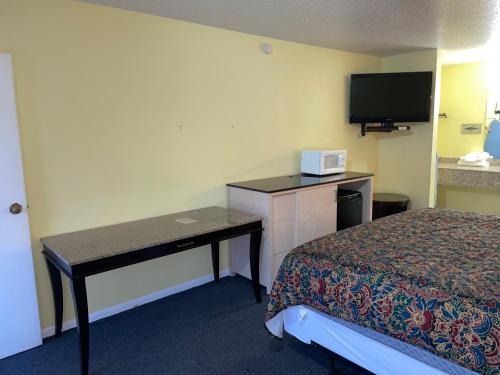 a hotel room with a desk and a bed and a tv at Executive Inn in San Saba