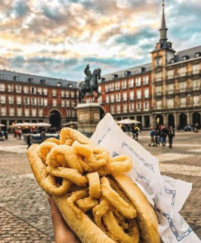 a person holding a hot dog and some onion rings at APARTAMENTO MADRID Norte in San Sebastián de los Reyes