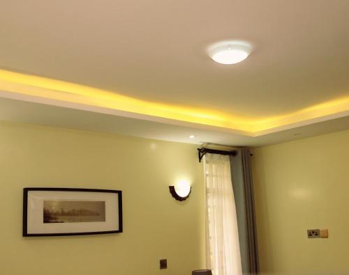 a room with a ceiling with a light and a window at The Cottage Residence Karen in Nairobi