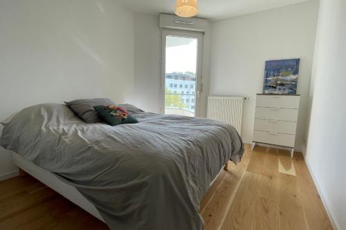 une chambre avec un grand lit avec une fenêtre dans l'établissement Les Capucines - Appartement moderne proche centre d'Annecy, à Annecy