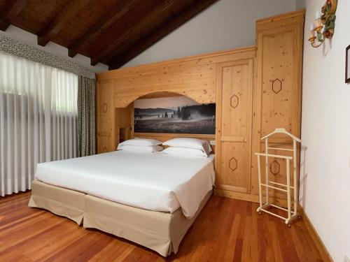 a bedroom with a large white bed with a wooden wall at La capr'allegra in Gallio