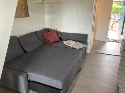 a gray couch with a pillow on it in a living room at Gustavsro i Apelviken Annex 1 in Varberg