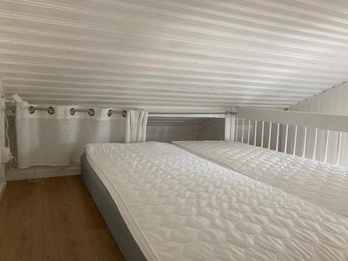 uma cama branca num quarto com um tecto branco em Gustavsro i Apelviken Annex 1 em Varberg