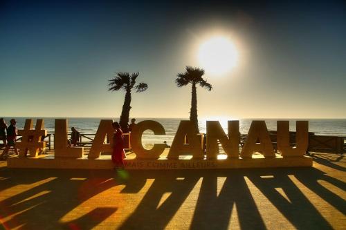 a woman standing in front of a sign on the beach at T3 - TERRASSE 30 m2 VUE OCEAN, 2 CHAMBRES, parking privatif et piscine en été in Lacanau-Océan