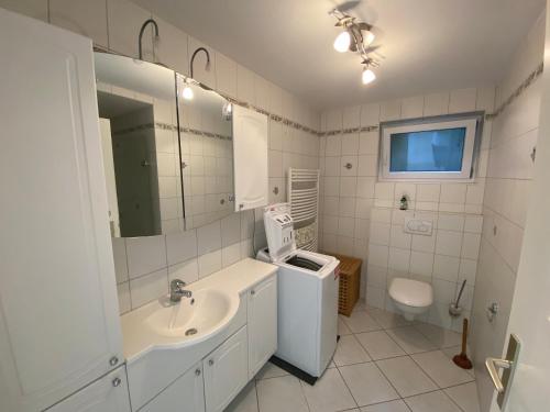 ein weißes Bad mit einem Waschbecken und einem WC in der Unterkunft Ferienwohnung Löwenzahn in Fischingen