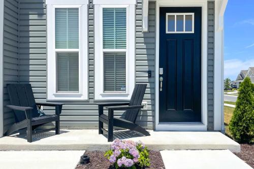 two chairs on the front porch of a house with a blue door at Beach Shuttle and Pool Bishops Landing Townhome in Millville