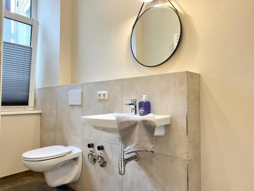 Un baño con lavabo, inodoro y espejo. en Apartment an der Altstadt # 1, en Hameln