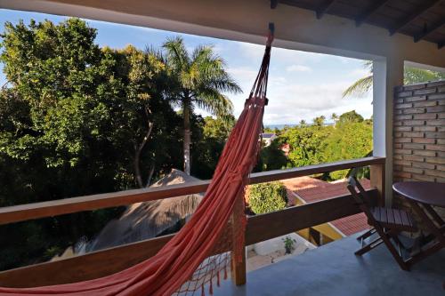 a hammock on a balcony with a view of the ocean at Pousada Arraial Colonial in Arraial d'Ajuda