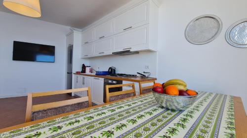 eine Küche mit einem Tisch, auf dem eine Obstschale steht in der Unterkunft Barracuda Apartment in Sarandë