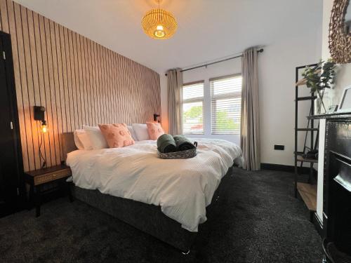 a bedroom with a bed with white sheets and pink pillows at Modern mid terrace villa, Royston, Barnsley in Royston
