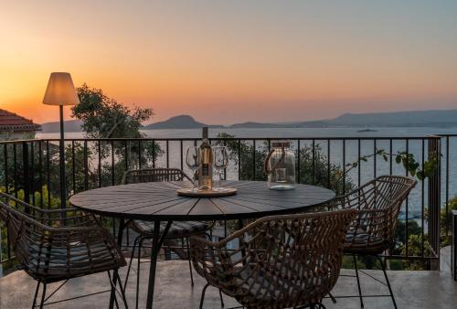 a table and chairs on a balcony with the sunset at TIS YAYAS apartments in Pylos