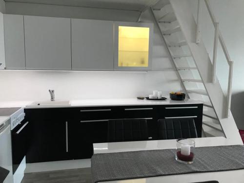 une cuisine avec des placards noirs et blancs et un escalier dans l'établissement Näköalahuoneisto 426, à Syöte
