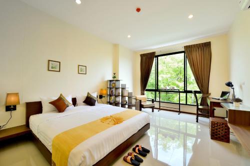 a bedroom with a bed and a desk and a window at The Choice Hotel - Adults Only in Bangkok