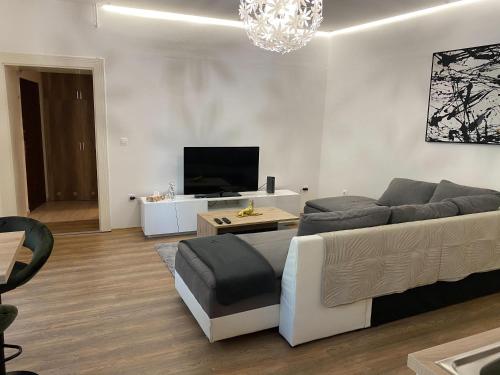 ein Wohnzimmer mit einem Sofa und einem Flachbild-TV in der Unterkunft Várker 9 Apartman in Sopron