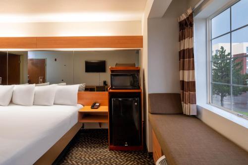 a hotel room with a bed and a desk and a window at Microtel Inn & Suites by Wyndham Salt Lake City Airport in Salt Lake City