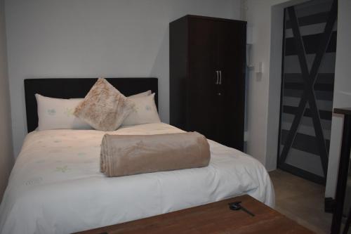 Una cama con una bolsa marrón encima. en Langbeentjie Inn en Ciudad del Cabo