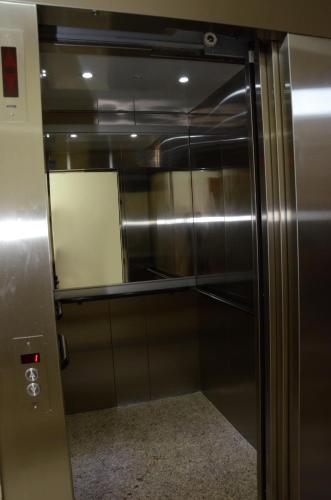 a metal elevator with a glass door with a mirror at Hotel Monte Carlo in São João del Rei