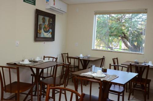 a dining room with tables and chairs and a window at Hotel Monte Carlo in São João del Rei