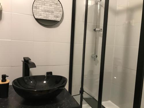 y baño con lavabo negro y ducha. en La maison de Sloan en Guéret