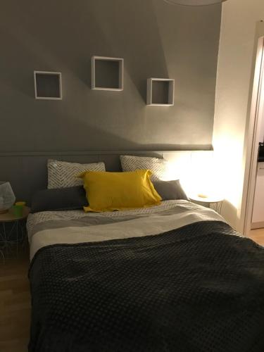 um quarto com uma cama com uma almofada amarela em La maison de Sloan em Guéret
