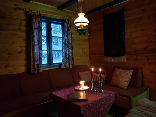 een woonkamer met een tafel met twee kaarsen erop bij Hytte ved innsjø in Landsem