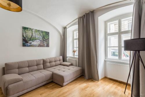 Una sala de estar con un sofá y dos ventanas. en Servus at Naschmarkt II, en Viena