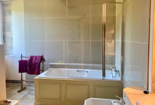 La salle de bains est pourvue d'une baignoire et d'une douche en verre. dans l'établissement Logis de La Touche, à Saint-Hilaire-des-Loges