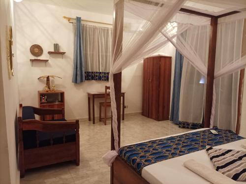 a bedroom with a canopy bed and a desk at Zanzicrown in Nungwi