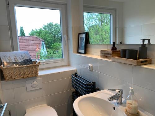 a bathroom with a sink and a toilet and two windows at Lille Schlei Hus in Boren