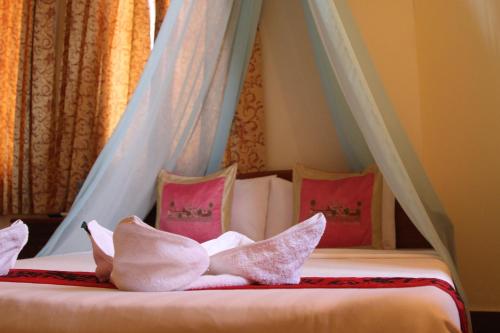 a bed with pink and white pillows on it at Golden Noura Villa-Pub & Restaurant in Phnom Penh