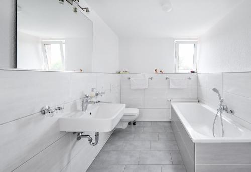 ein weißes Badezimmer mit zwei Waschbecken, einer Badewanne und einem WC in der Unterkunft Ferienwohnung im Leipziger Neuseenland in Böhlen